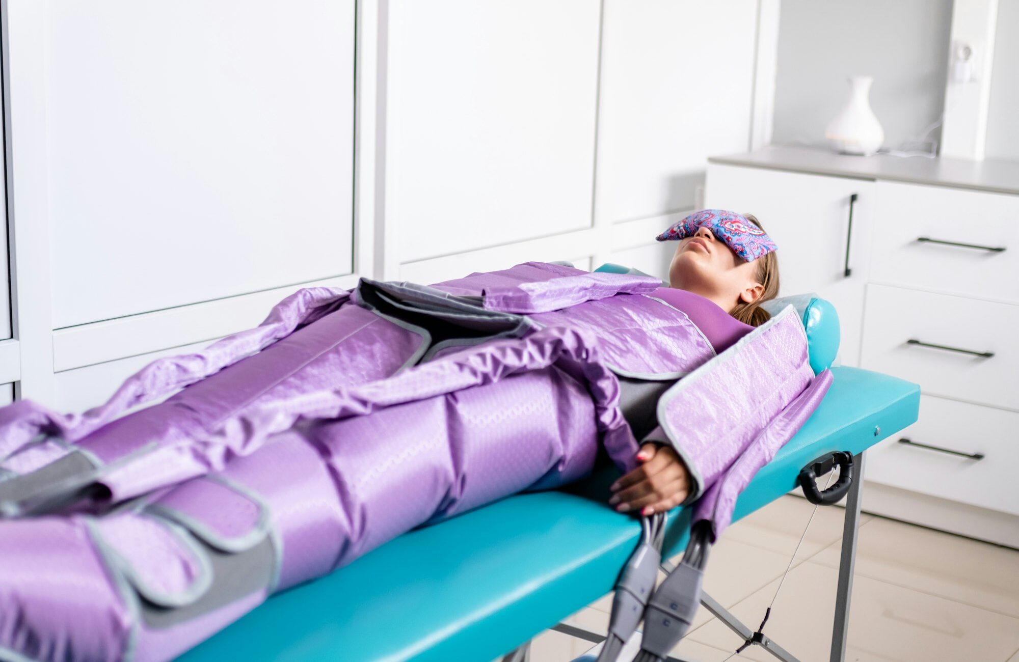 Woman lying with closed eyes during pressotherapy session in beauty clinic. Concept