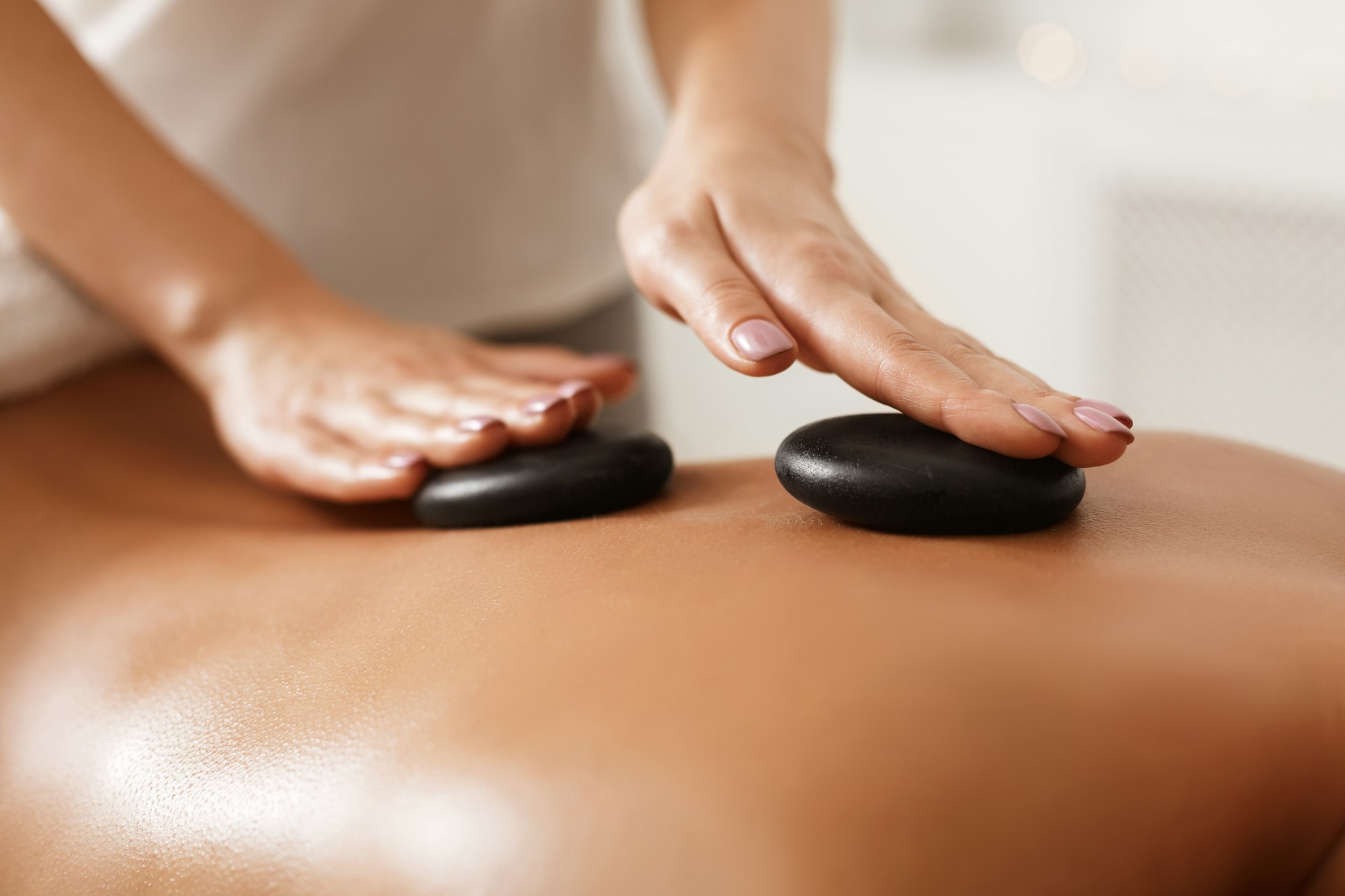 Masseur doing back hot stone massage, closeup